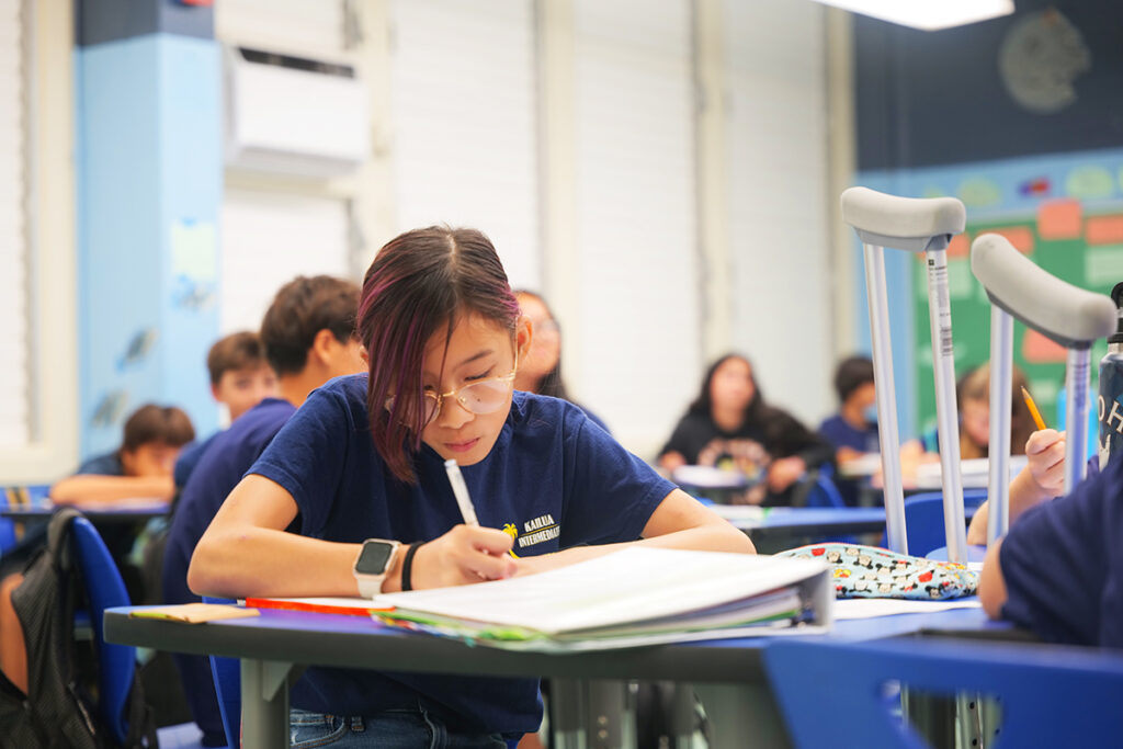 Students at their desk, one student taking notes