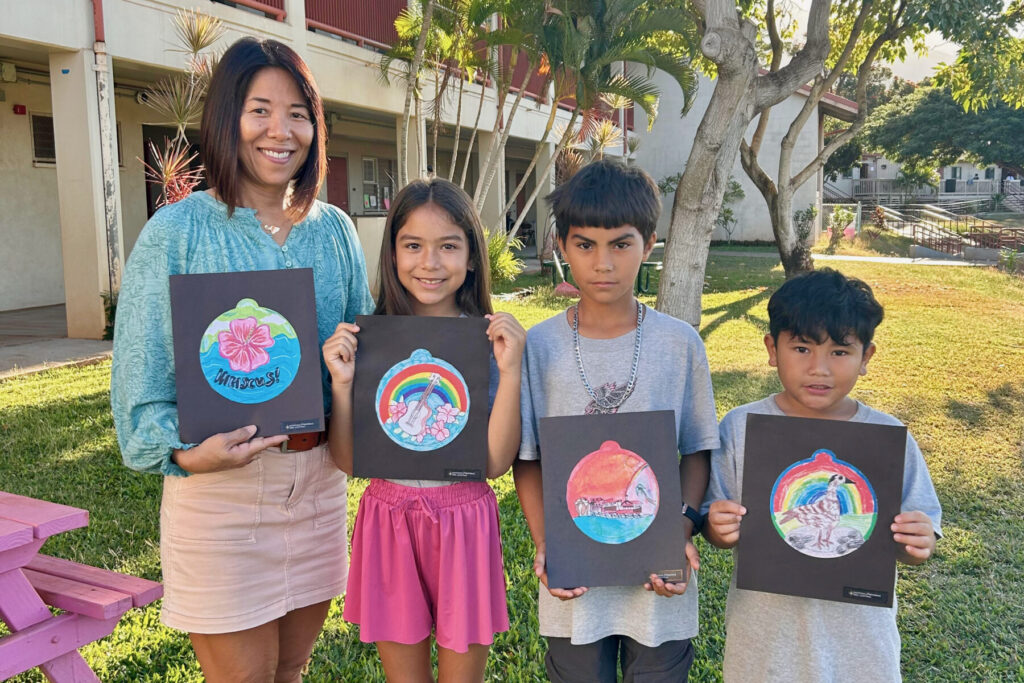 Three students with teacher holding drawn ornaments