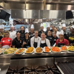 A group photo is taken inside of a kitchen.