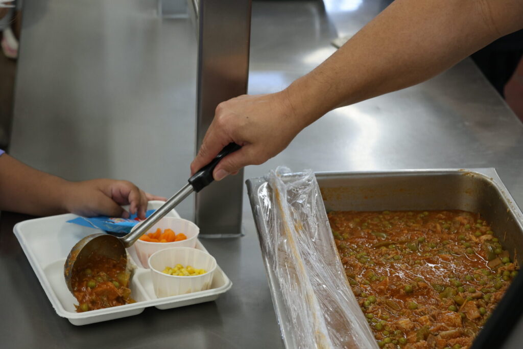 Cafeteria staff serving pork guisantes