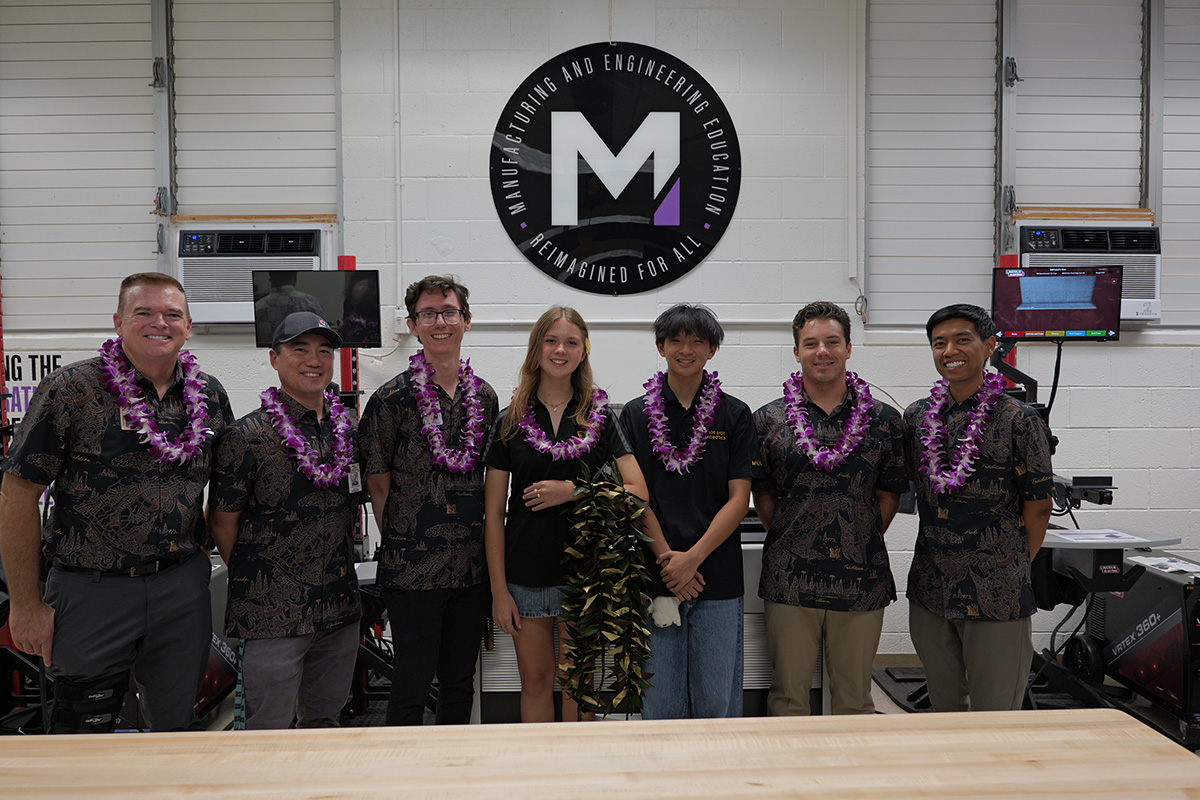 Mililani High students and staff wearing lei stand next to each other in the lab.