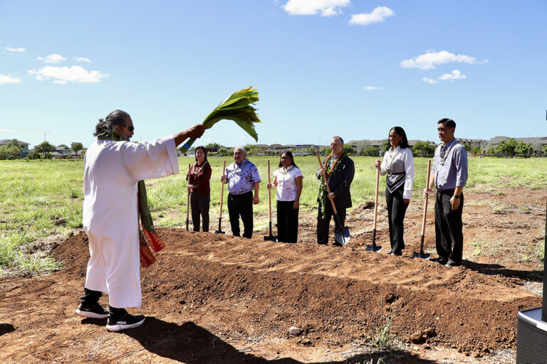 A kahu performs a blessing with ti leaves in front of dignitaries during the groundbreaking ceremony.