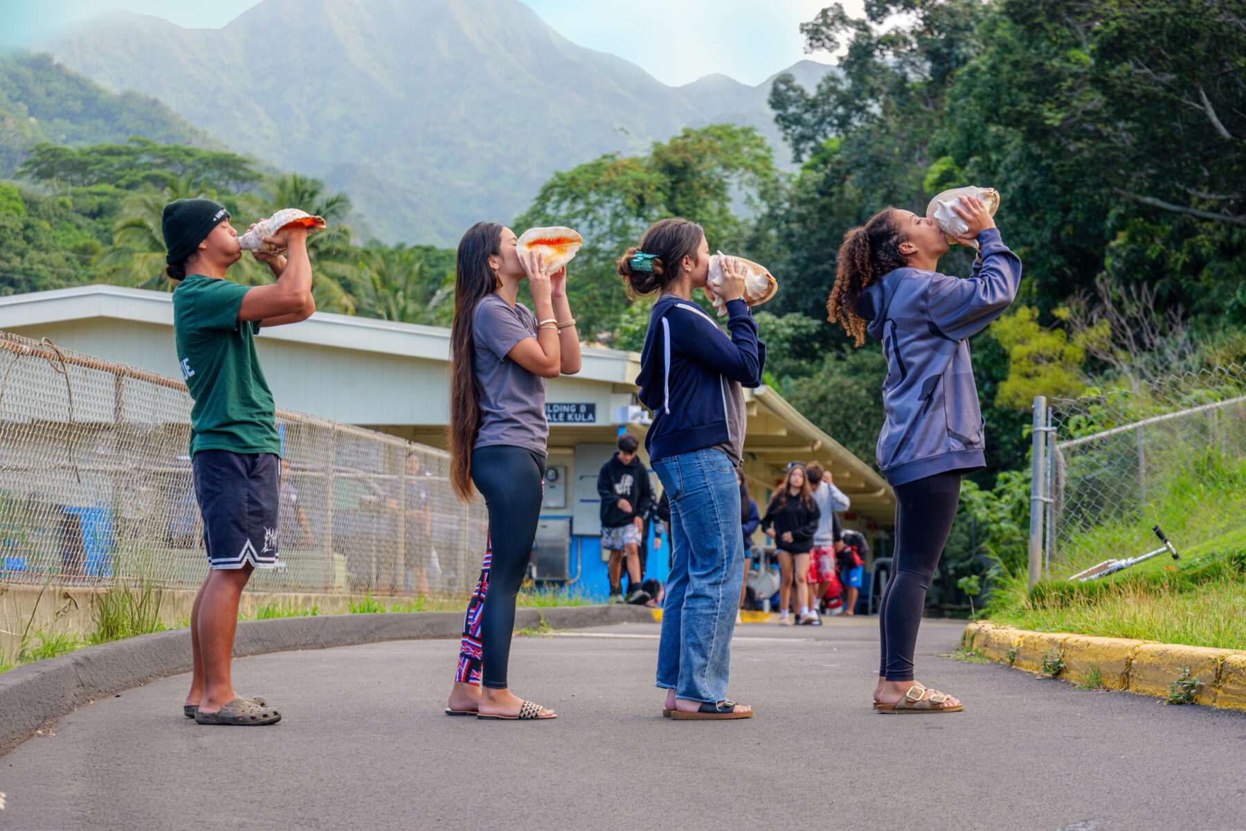 Four students blowing into conch shells