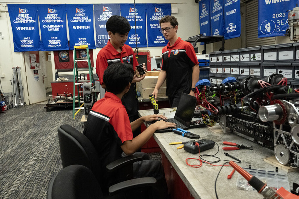Three student interns work with tools.