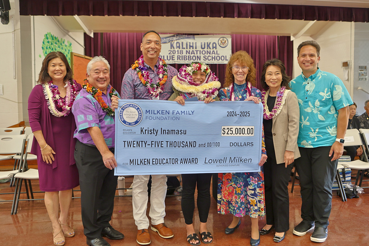 Teacher Kristy Inamasu poses for a group photo with administrators and politicians while holding a check for $25,000.