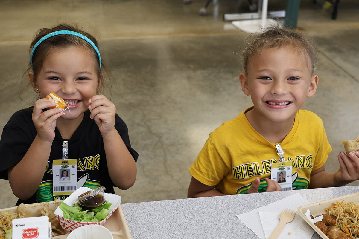 Students at Helemano Elementary smile with their mandarins served during lunch.