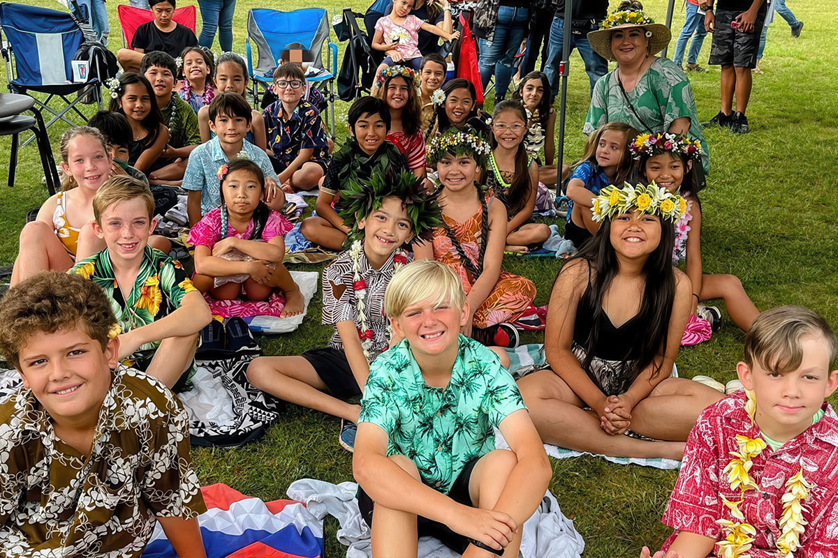 students sitting down on a grass field