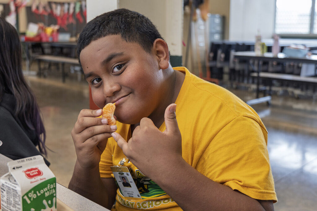 A student at Helemano Elementary flashes a shaka while eating a mandarins served during lunch.