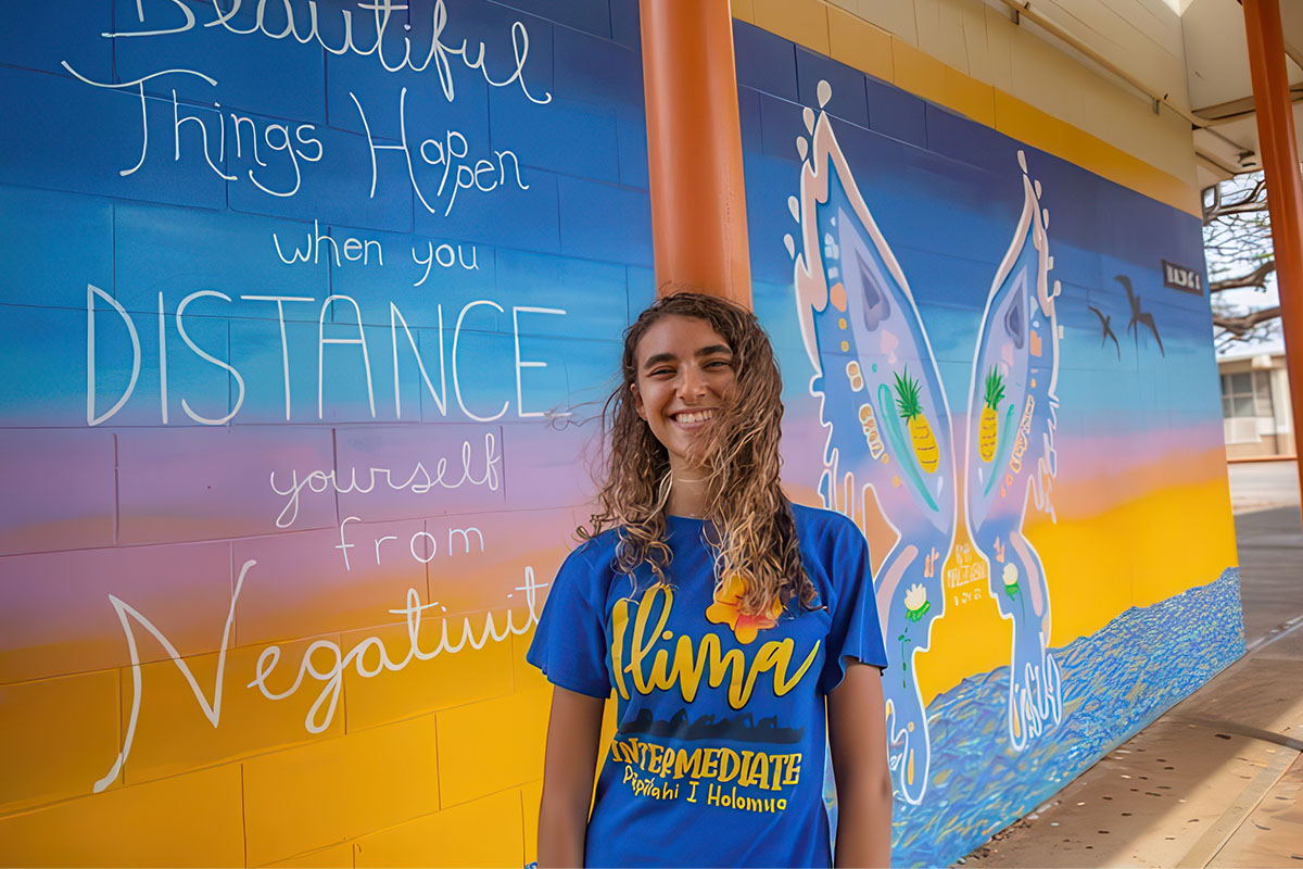 student in front of mural