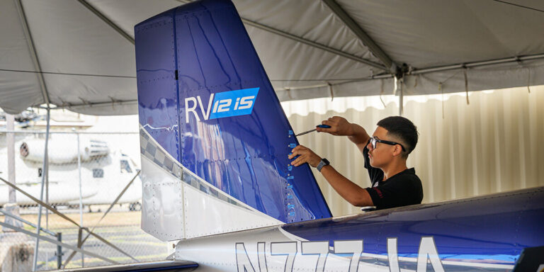 A boy uses a screwdriver to fix an airplane.
