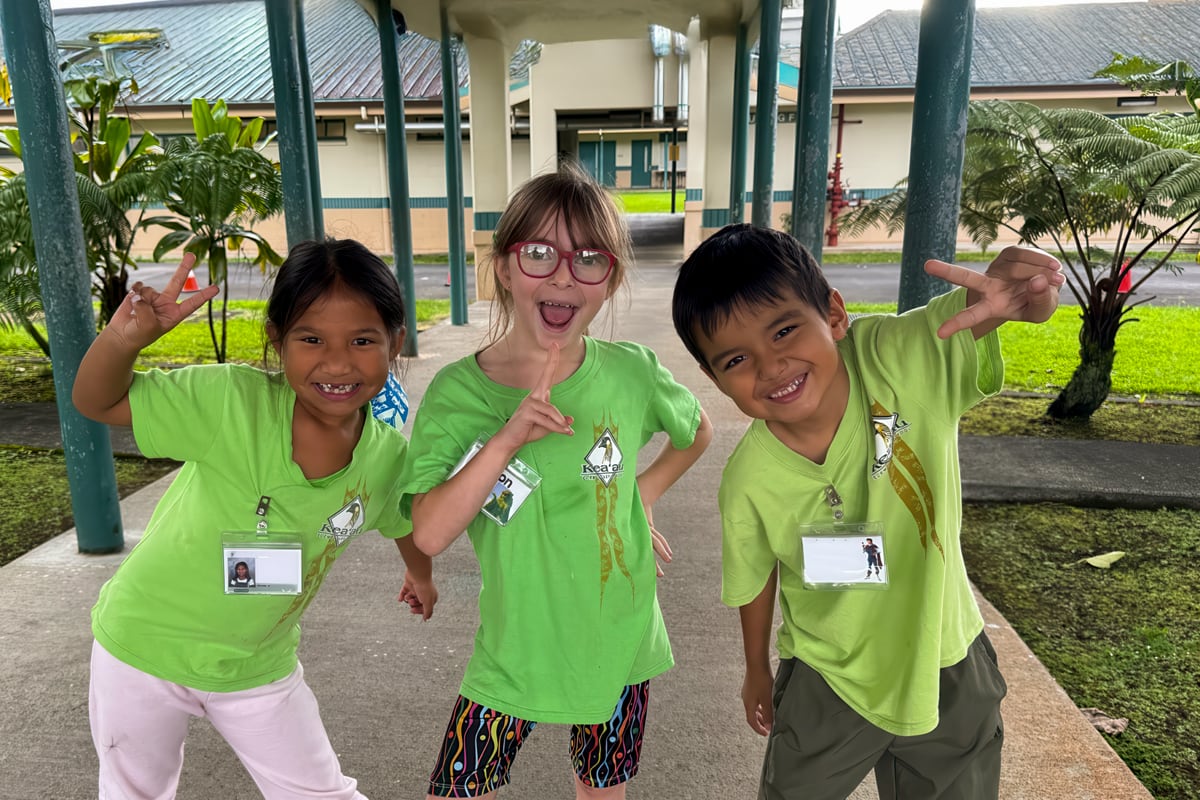 three students showing the peace sign