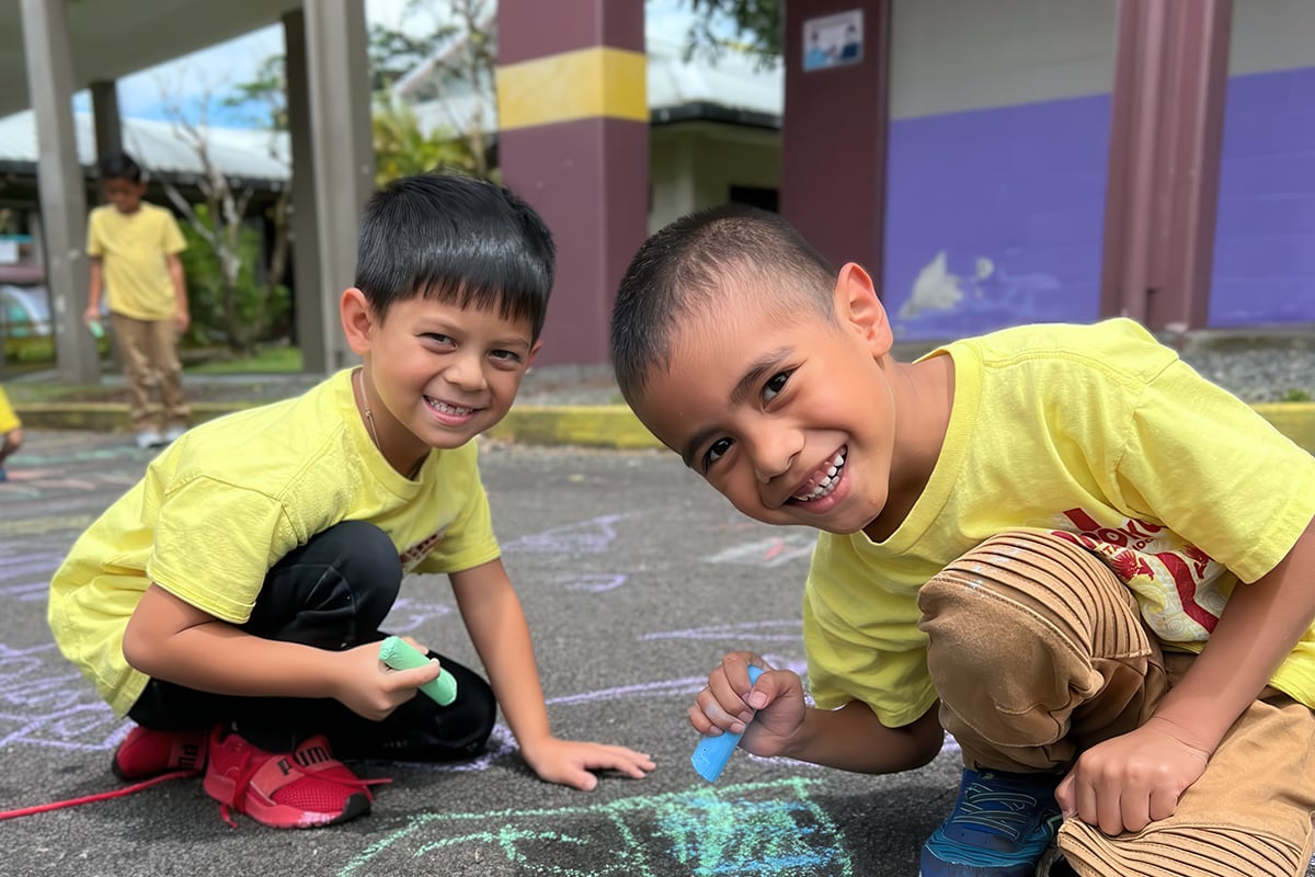 students drawing with chalk on pavement