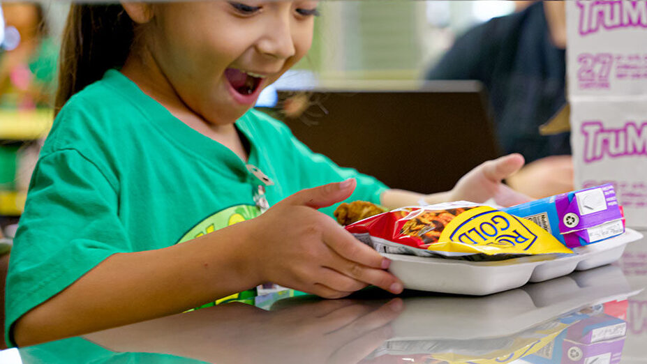 A student smiles while picking up lunch.