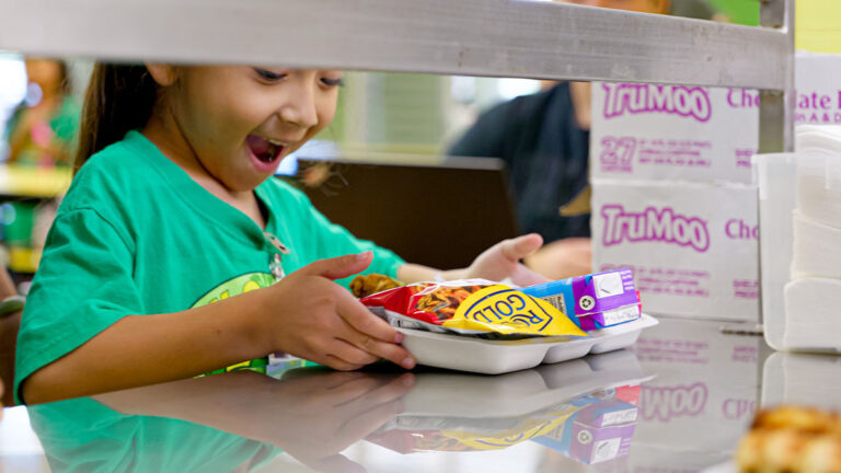 A student smiles while picking up lunch.