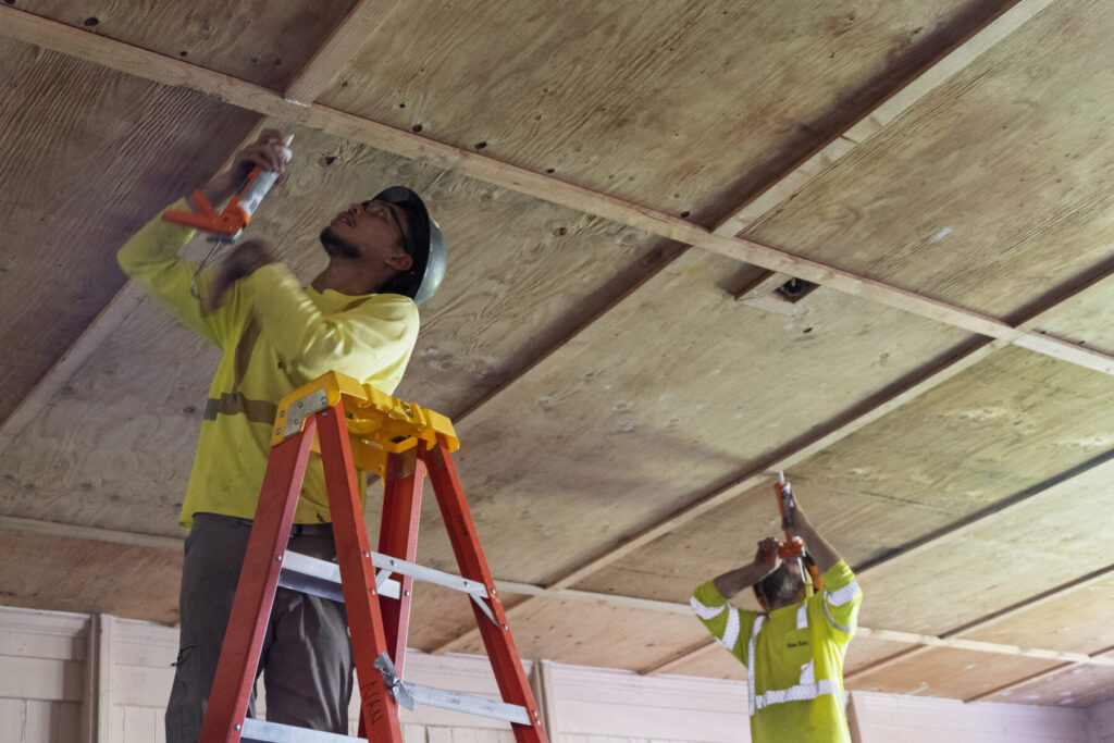Construction workers repair a ceiling.