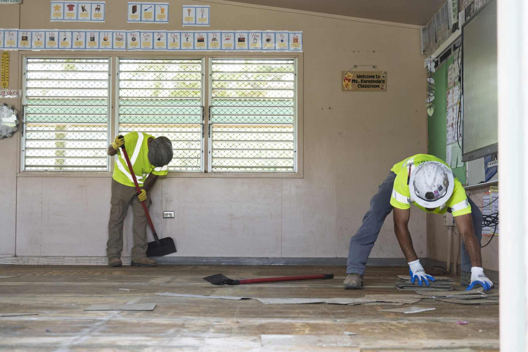 Two construction workers repair a damaged classroom.