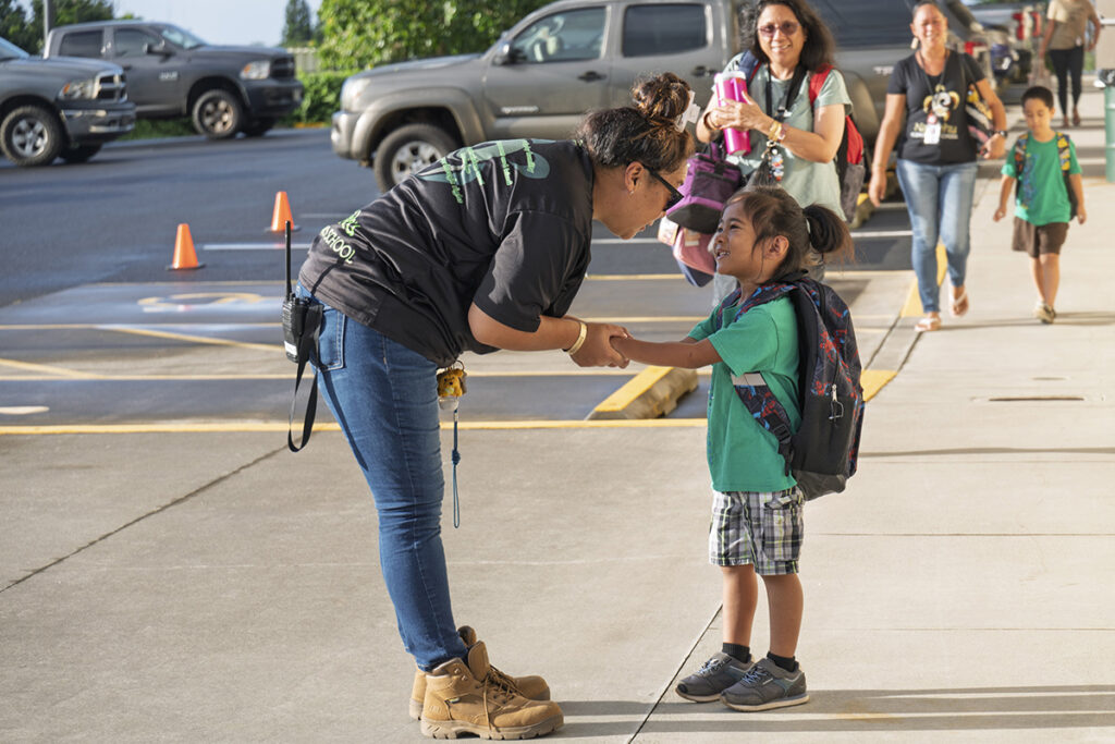 A Nā‘ālehu staff member greets a student.