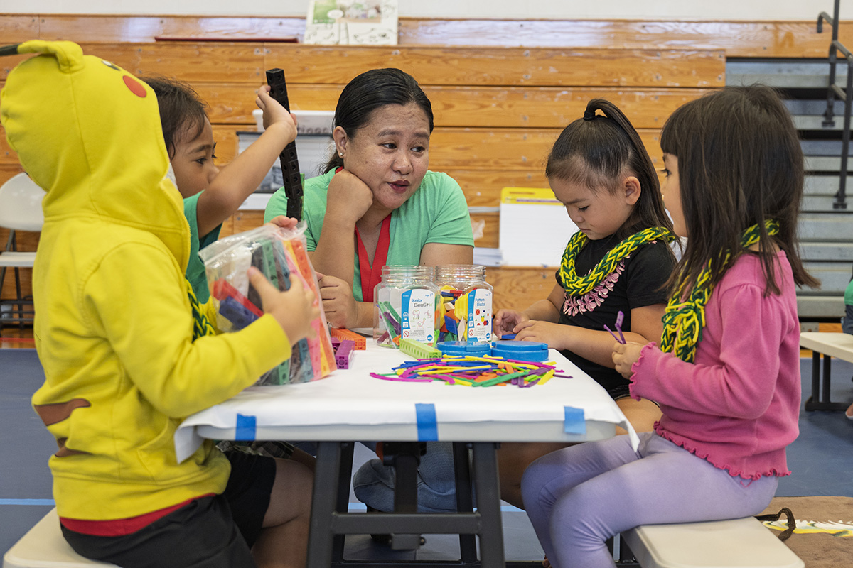 A Nā‘ālehu teacher sits at a table with four students.