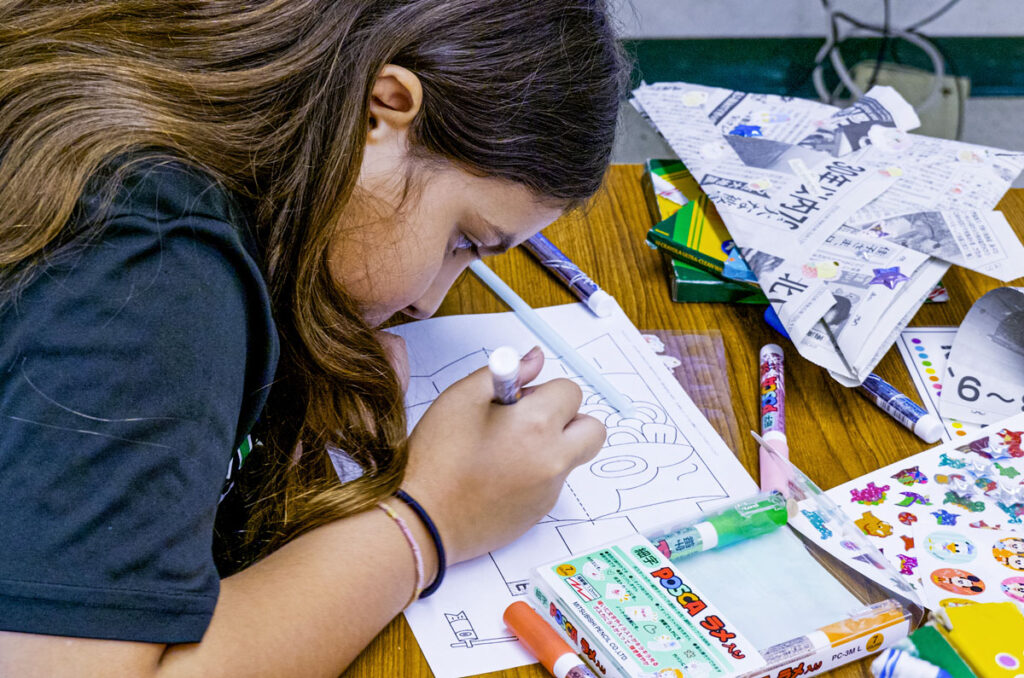 Young school girl making illustration artwork on a table.