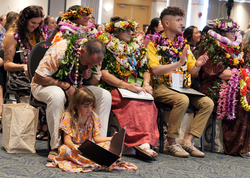 Makawao Elementary teacher Troy "Leven" Abshire Jr. looks at his award with his daughter seated next to him.