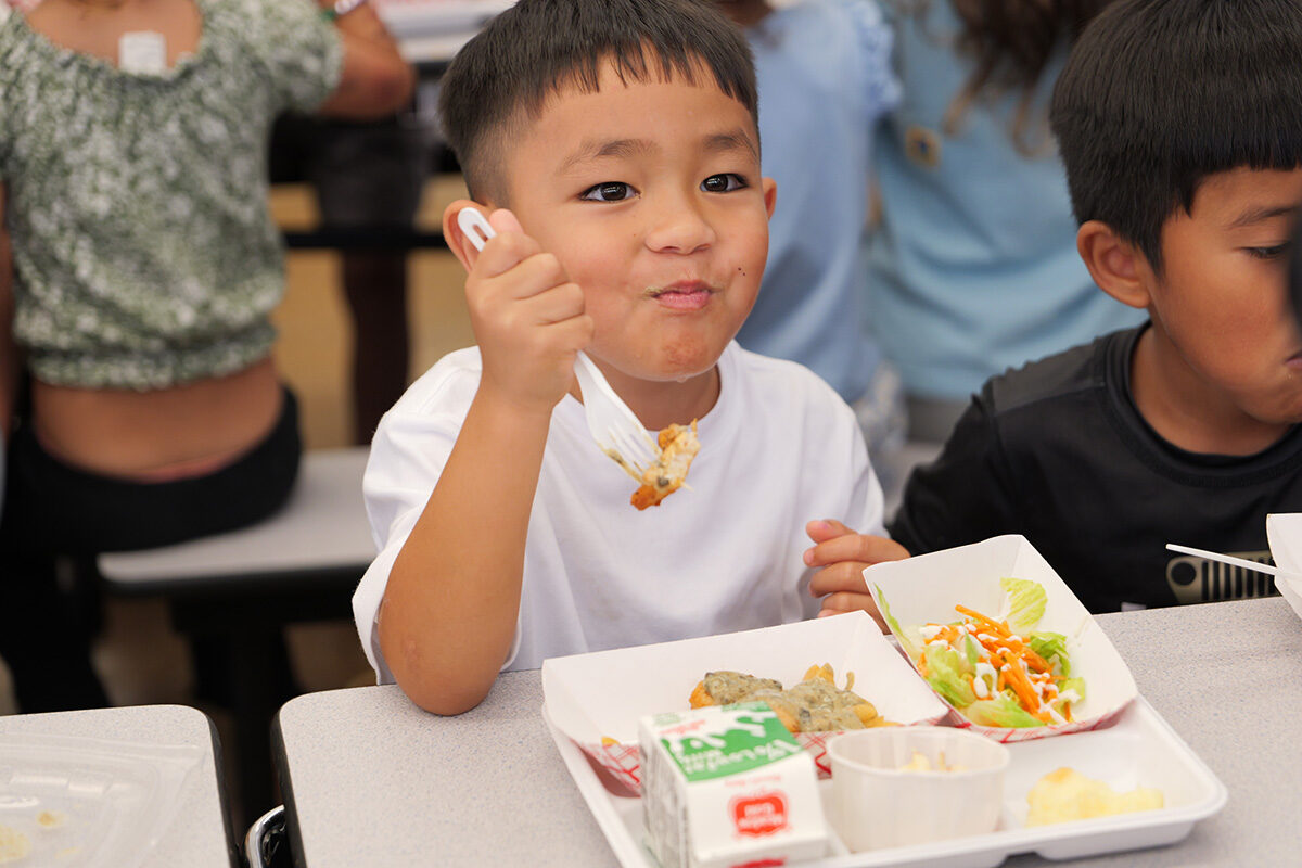 A student enjoys a lunch of lūʻau leaves mixed into chicken pasta florentine.