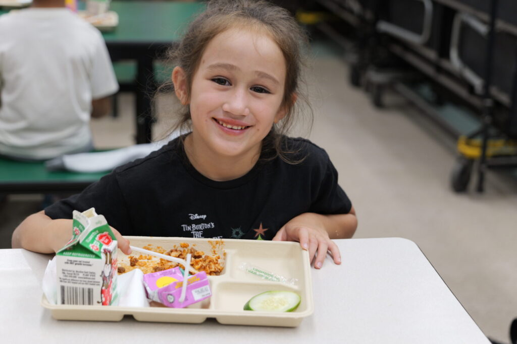 Student smiling with lunch tray.