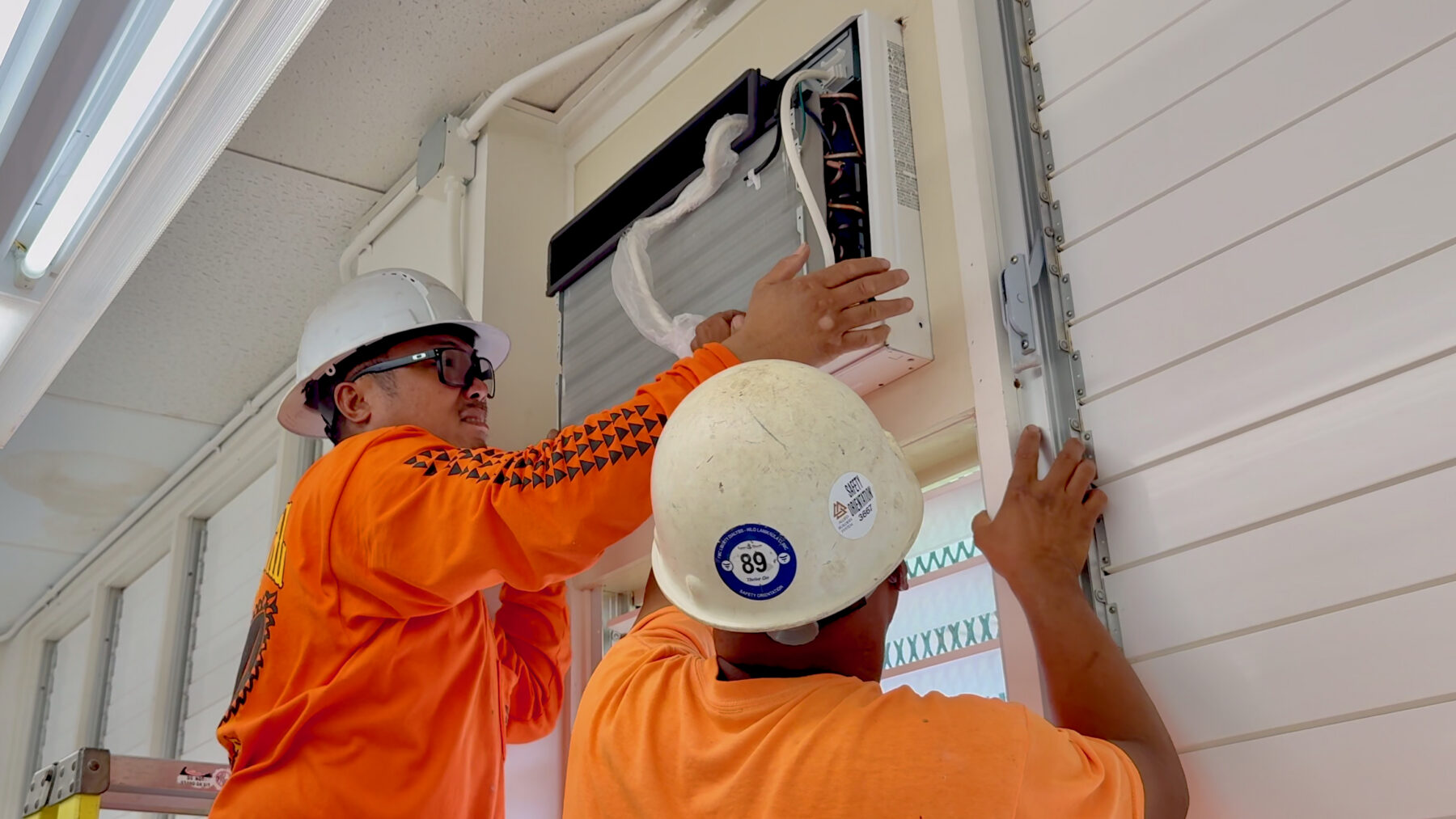 Workers install a new window air conditioning unit at Robert Louis Stevenson Middle School over the summer break.